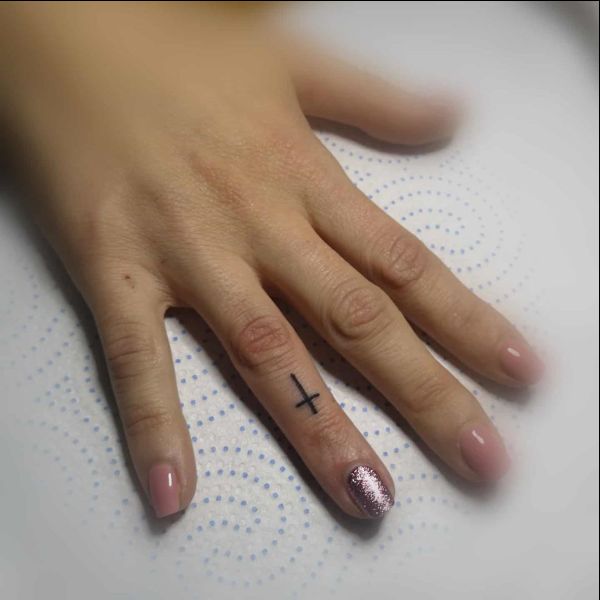 small cross tattoo on finger