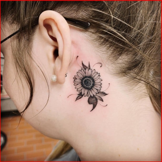 Microrealistic sunflower tattooed behind the ear